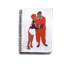 Caderno com capa em tons de vermelho e fundo branco e wire-o branco com ilustração de casal de homem negro e mulher negra de pé, trajando roupas em tons de vermelho. O caderno pra quem ama o dengo e que são a nossa cara.